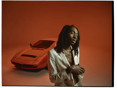 a man with dreadlocks standing next to a car