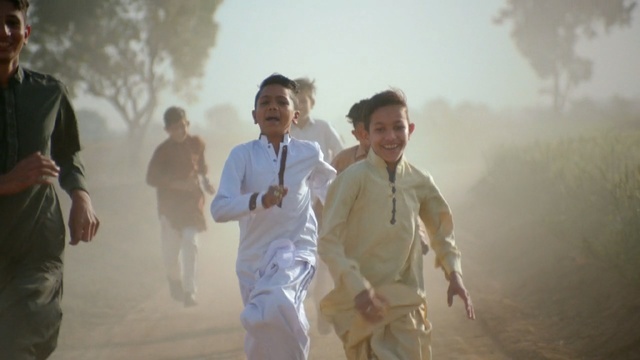 a group of young men running down a dirt road