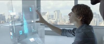 a woman is pointing at a futuristic display in front of a window