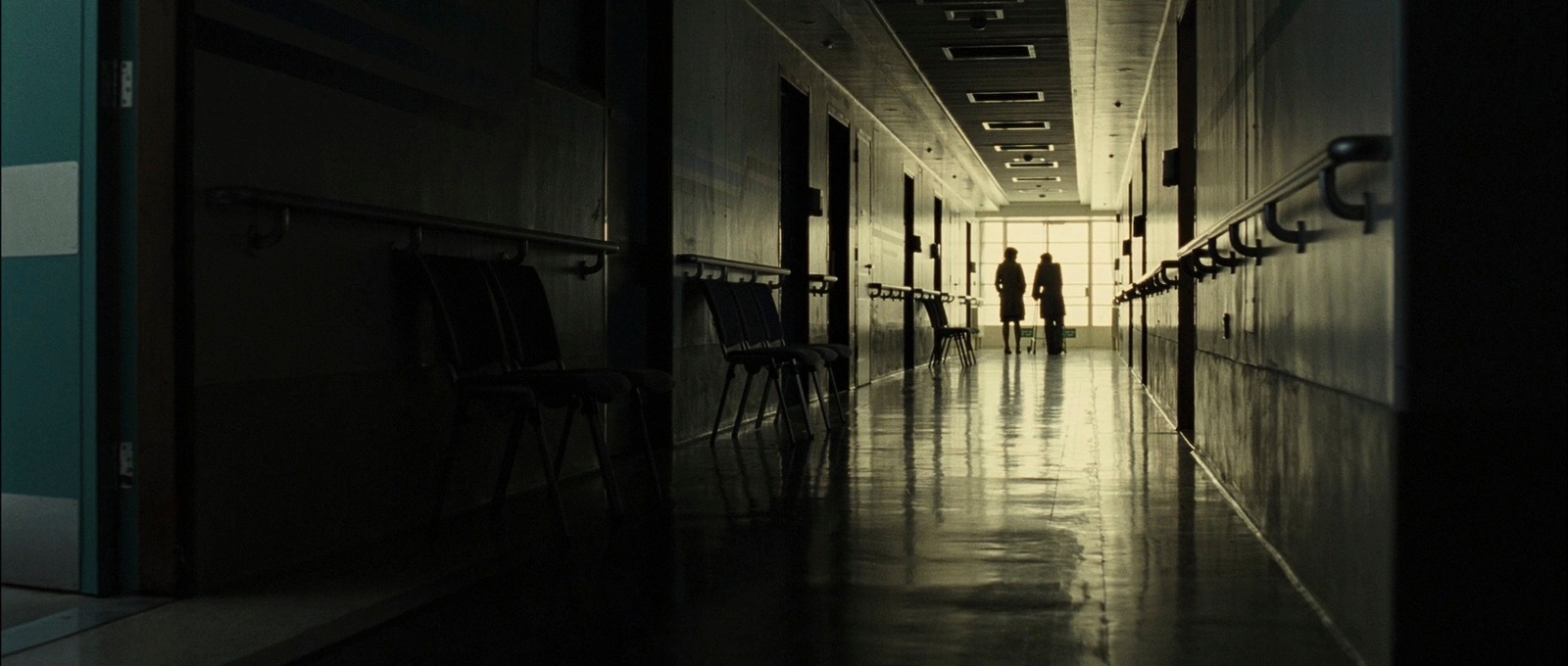 two people walking down a long hallway in a building