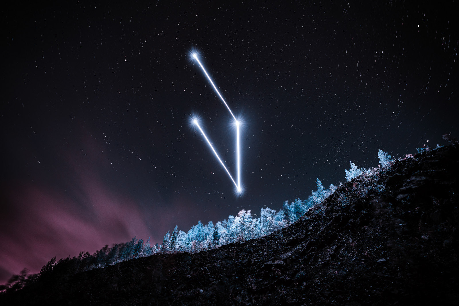 a pair of contrails are seen in the night sky