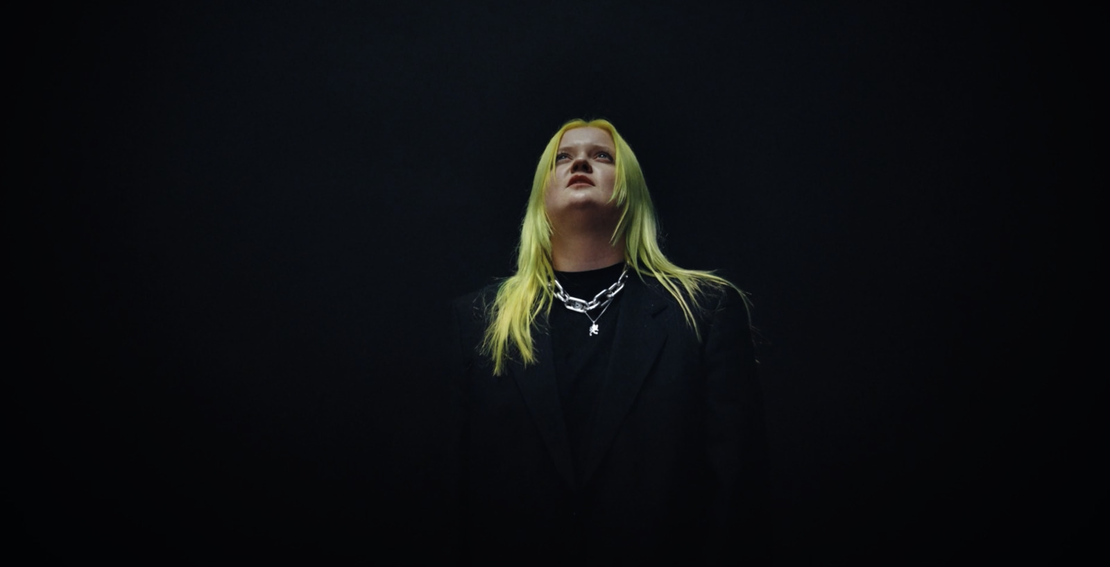 a woman with long blonde hair standing in the dark