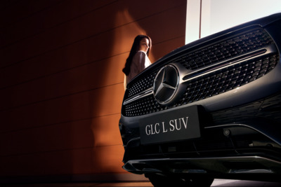 a woman standing next to a mercedes suv