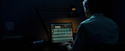 a man in a dark room looking at a computer screen