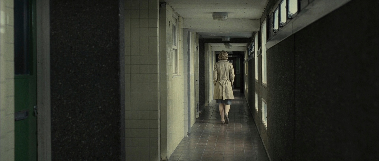 a woman walking down a long hallway in a building