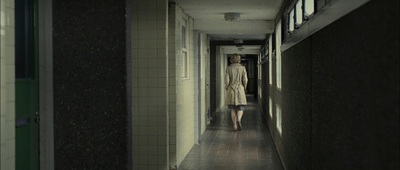 a woman walking down a long hallway in a building