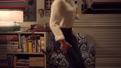 a woman standing in a living room next to a chair