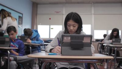 a girl is sitting at a desk with a laptop