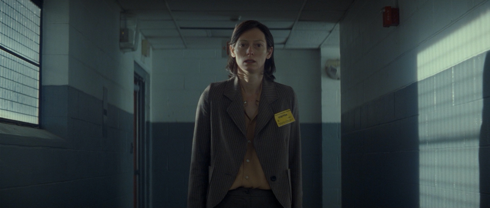 a woman standing in a hallway with a yellow tag on her jacket