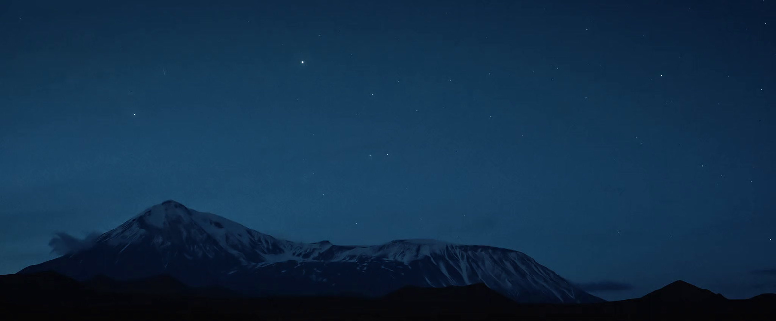 the night sky with stars above a snowy mountain