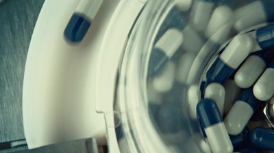 a glass jar filled with blue and white pills