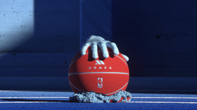 a hand holding a red ball on top of a tennis court