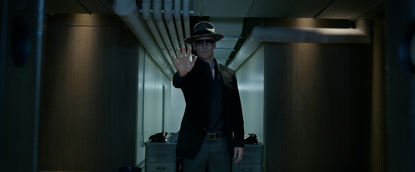 a man in a suit and hat standing in a hallway