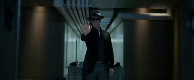 a man in a suit and hat standing in a hallway