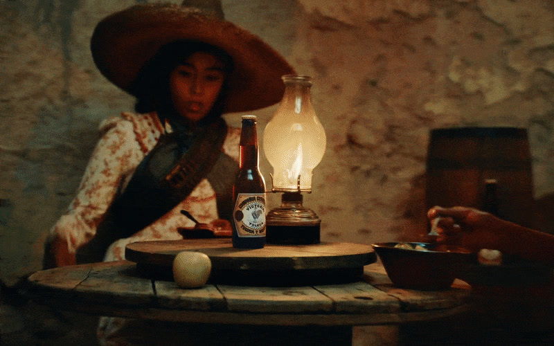 a woman sitting at a table with a bottle of wine