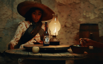 a woman sitting at a table with a bottle of wine