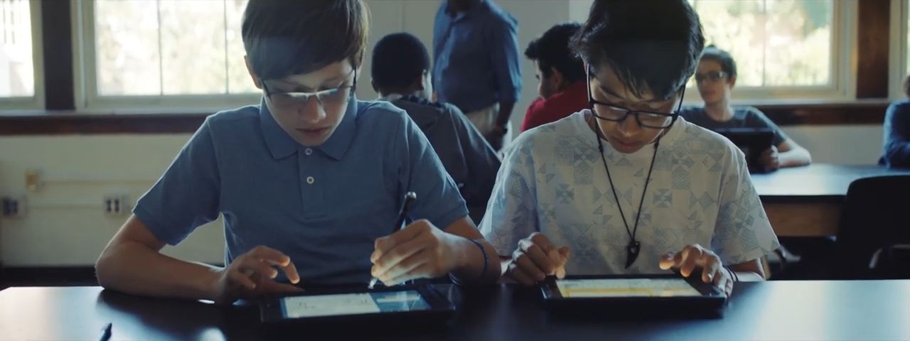 a couple of people sitting at a table with a tablet