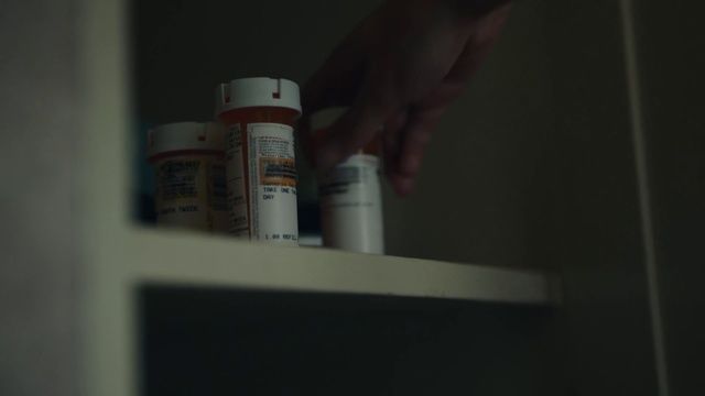 a person reaching for some medicine bottles on a shelf