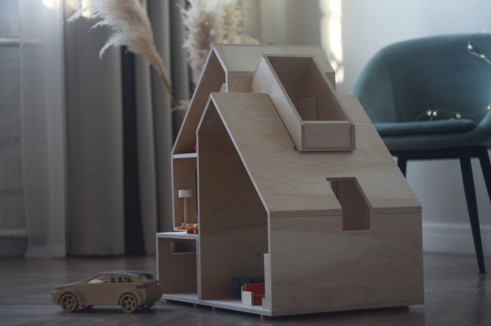 a toy car is parked in front of a doll house