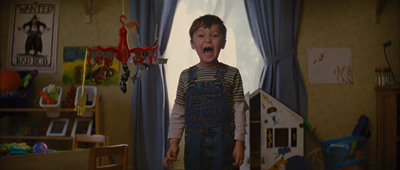 a young boy in overalls standing in a room