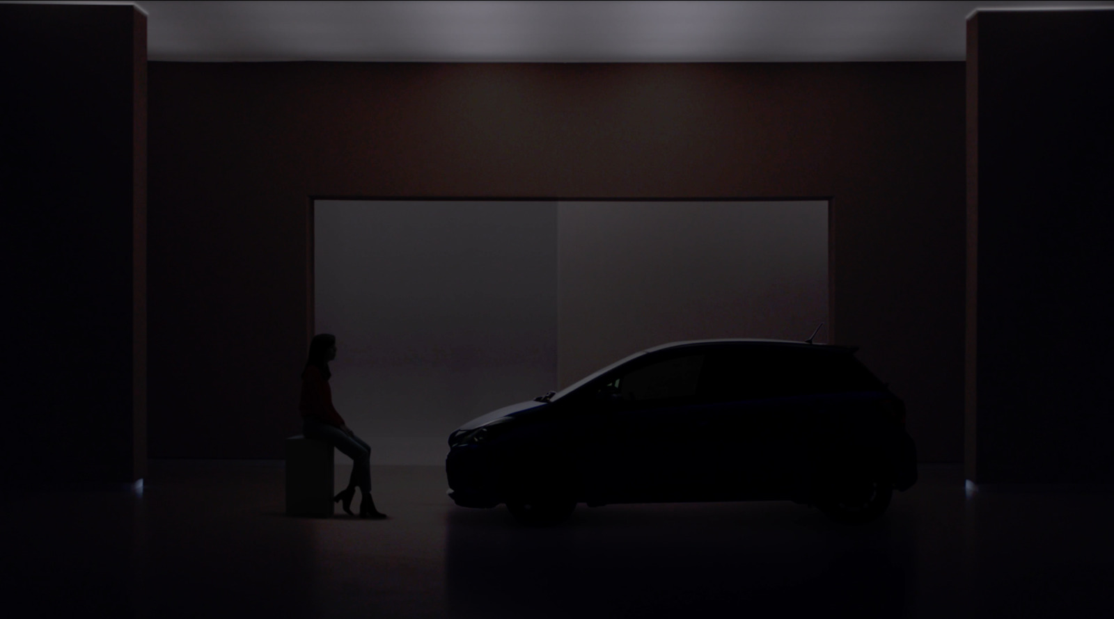 a woman sitting on a stool next to a car