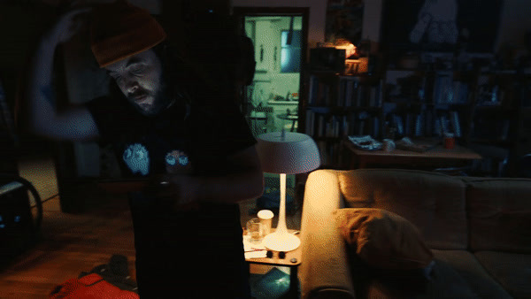 a man standing in a living room next to a lamp