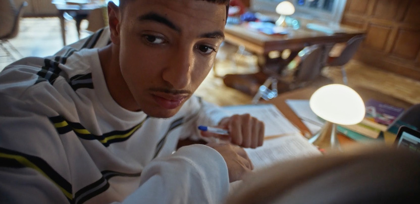 a young man sitting at a table with a pen and paper