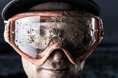 a man wearing a hat and goggles covered in dirt