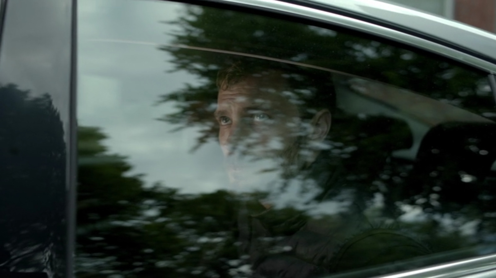 a man sitting in a car looking out the window