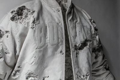 a man wearing a white jacket with holes in it