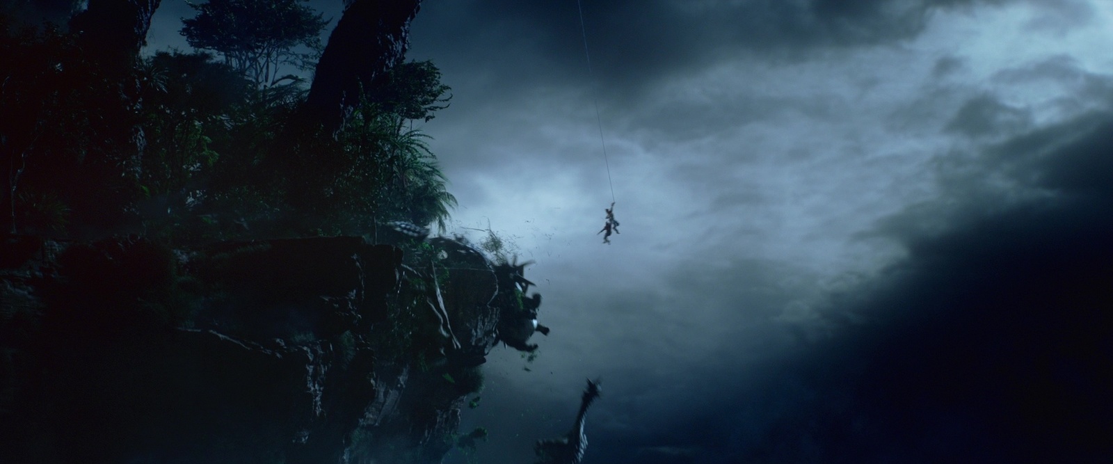 a man is suspended from a rope in a dark forest