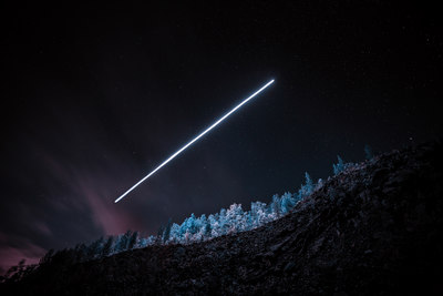 an airplane flying over a forest at night