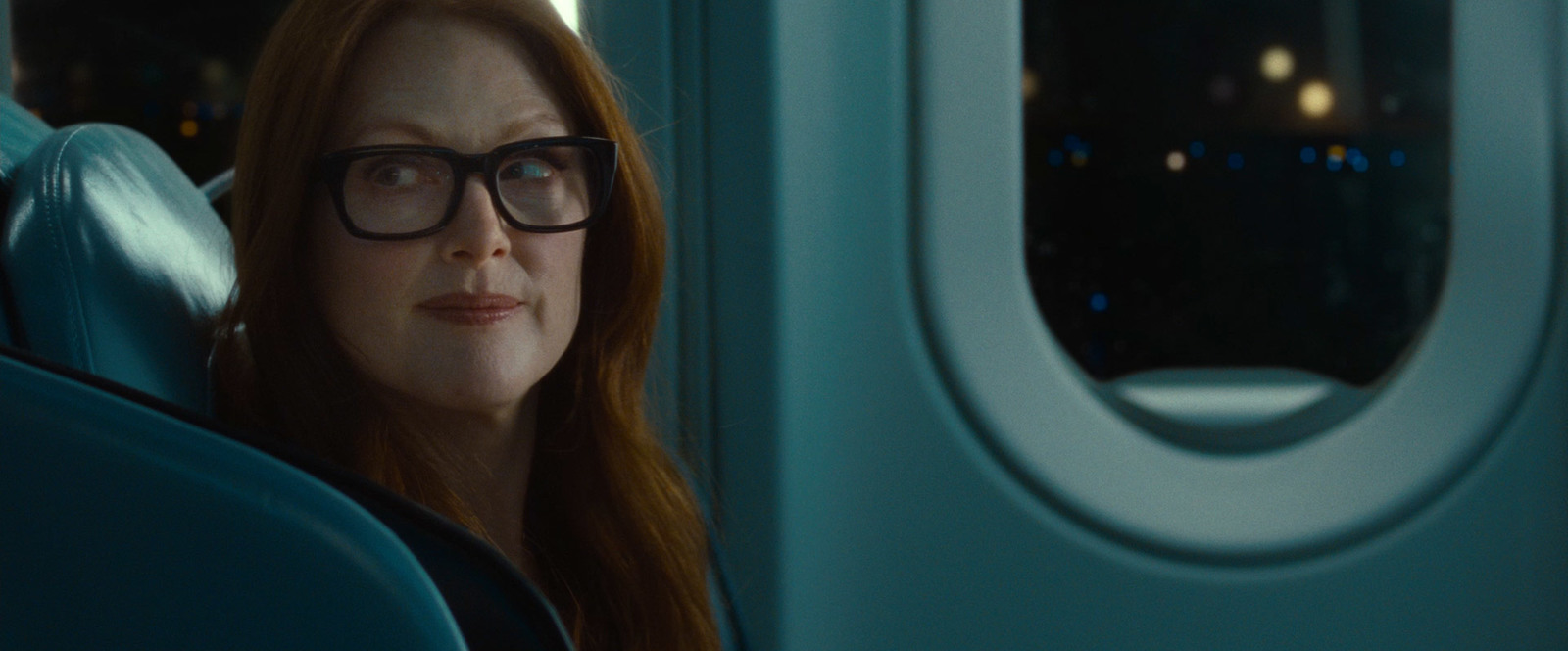 a woman with glasses looking out the window of an airplane