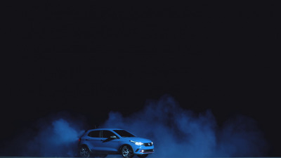 a car driving on a road with blue smoke coming out of it