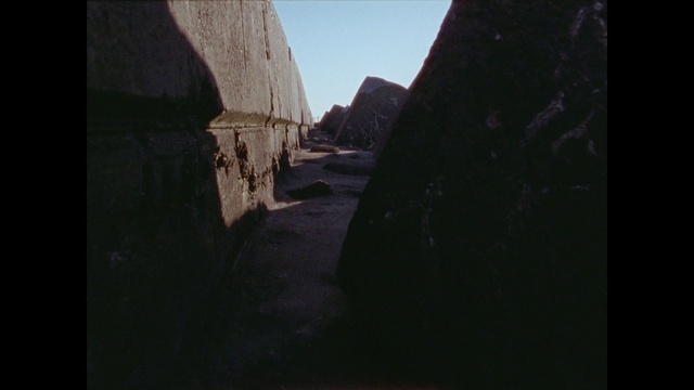 a narrow alley with rocks and a sky background