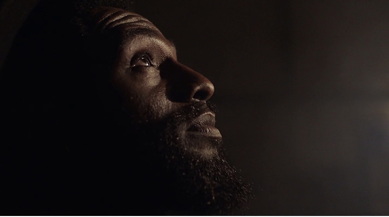 a man with a beard looking up at the light