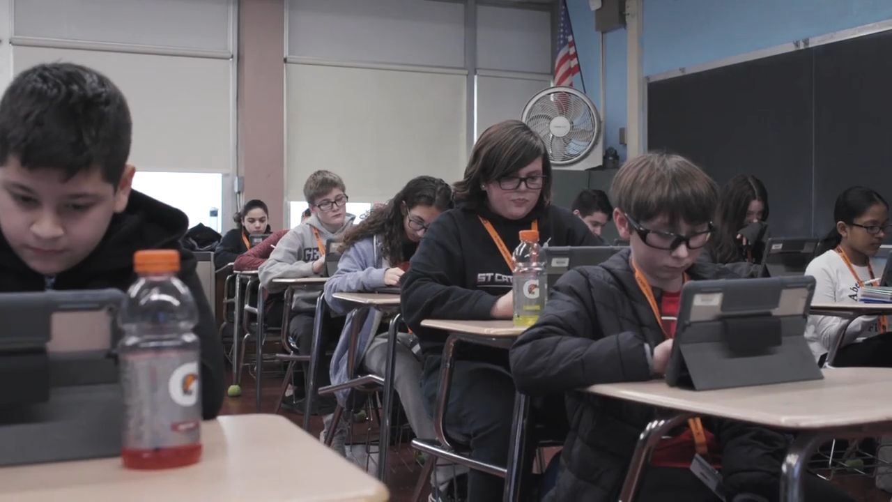 a group of kids sitting at desks using laptop computers