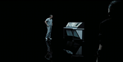 a man standing in the dark next to a computer