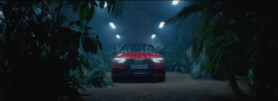 a red car driving through a forest at night