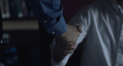 two people holding hands in front of a bookshelf