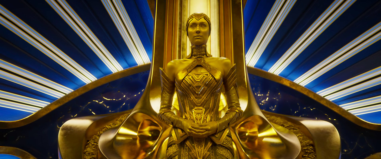 a gold statue sitting in front of a blue and white background