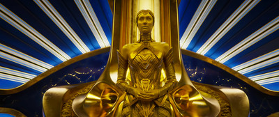 a gold statue sitting in front of a blue and white background