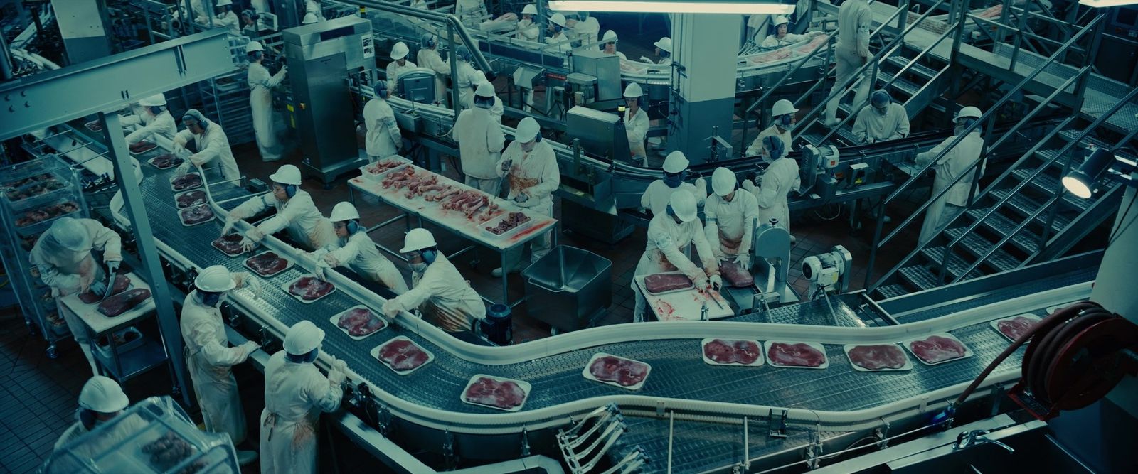 a factory filled with lots of workers working on meat