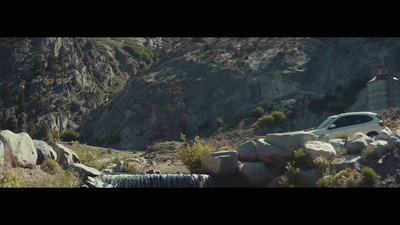 a car driving down a road next to a mountain