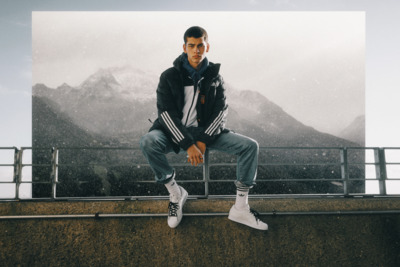 a man sitting on a ledge with mountains in the background