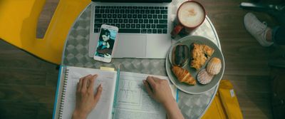 a person sitting at a table with a plate of food and a laptop