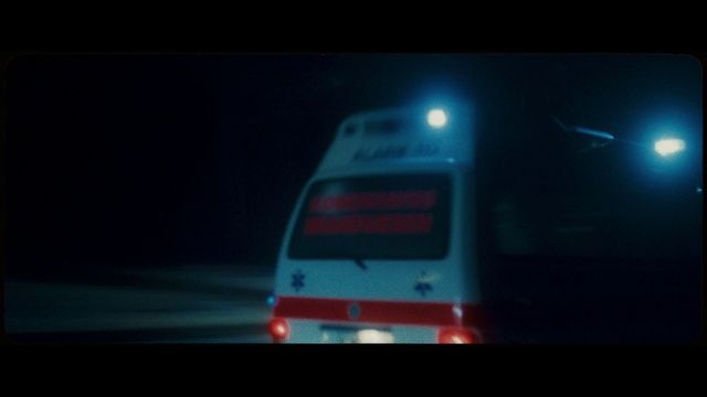 a white and red bus driving down a street at night