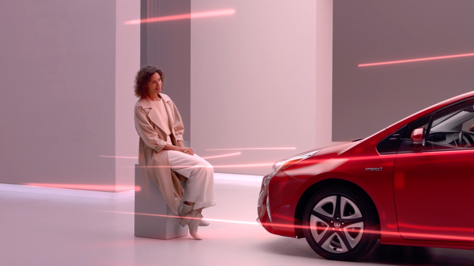 a woman sitting on a pillar next to a red car