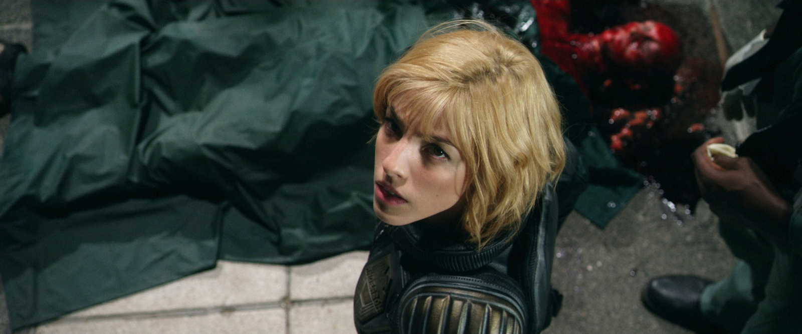 a woman with blonde hair standing next to a pile of garbage