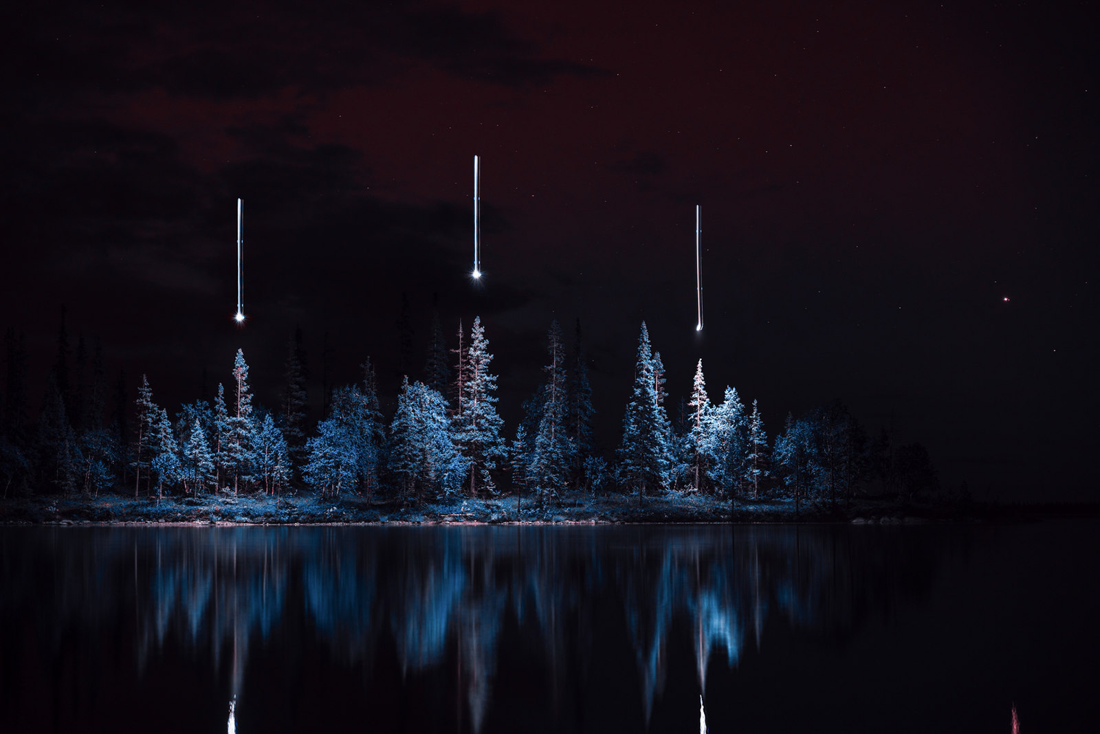 a night time scene of a lake and trees